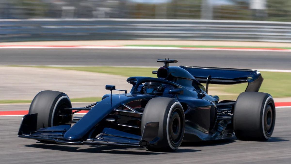 Mörkblå formel 1-bil utan synliga sponsormärken på väg genom en snabb kurva i dagsljus.