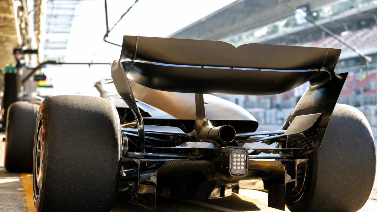 Bakvagn på en formel 1-bil med avgasröret och den bakre vingsektionen i skarpt motljus vid banan.