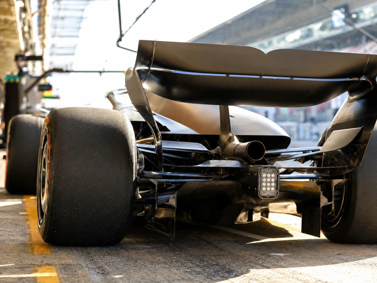 Bakvagn på en formel 1-bil med avgasröret och den bakre vingsektionen i skarpt motljus vid banan.